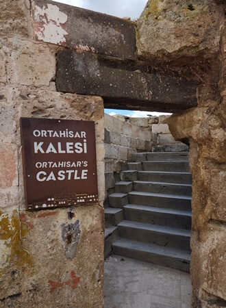 Ortahisar Kalesi giriş kapısı ve yukarıya çıkan taş merdivenler; Kapadokya’da kaleye giden yürüyüş yolu